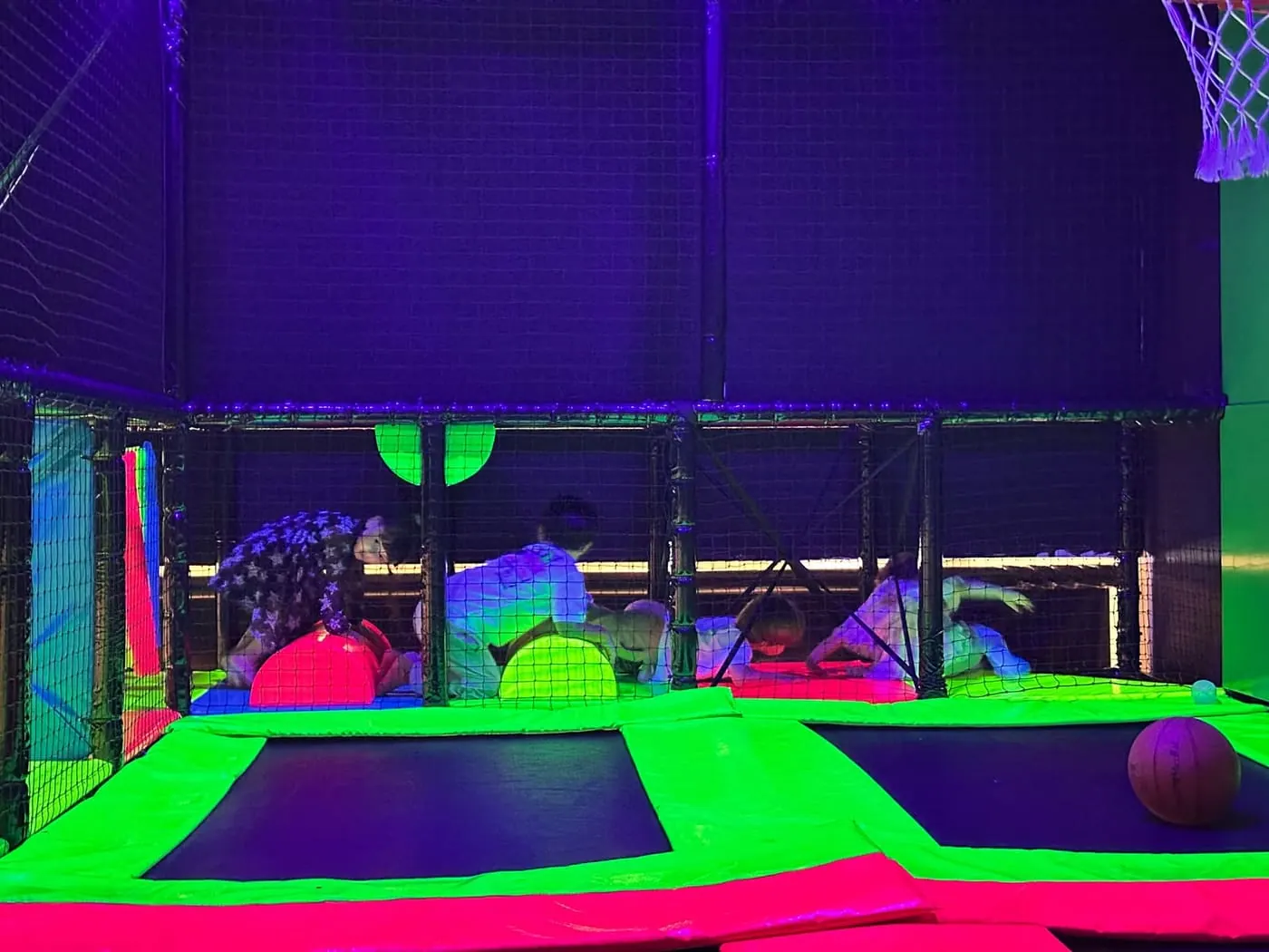 Criançada na arena de cama elástica sob a luz neon