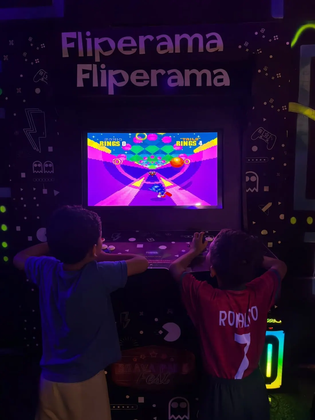 Criançada disputando um jogo de corrida no fliperama