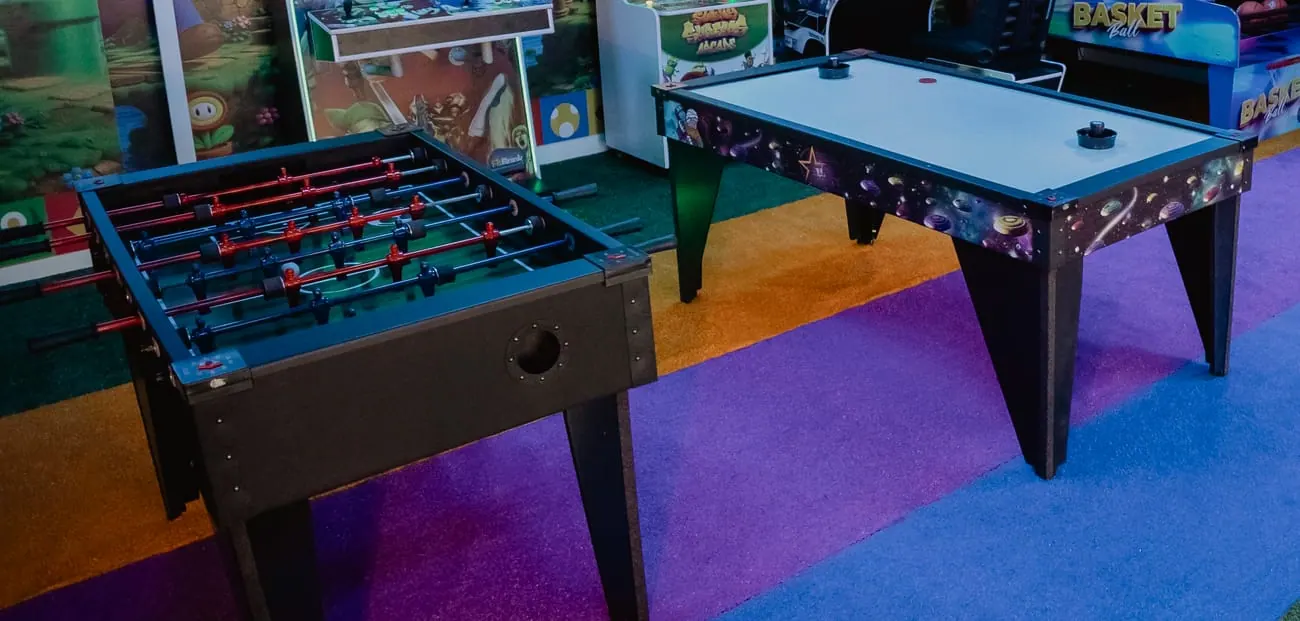Mesas de pebolim e aerohockey na sala de jogos